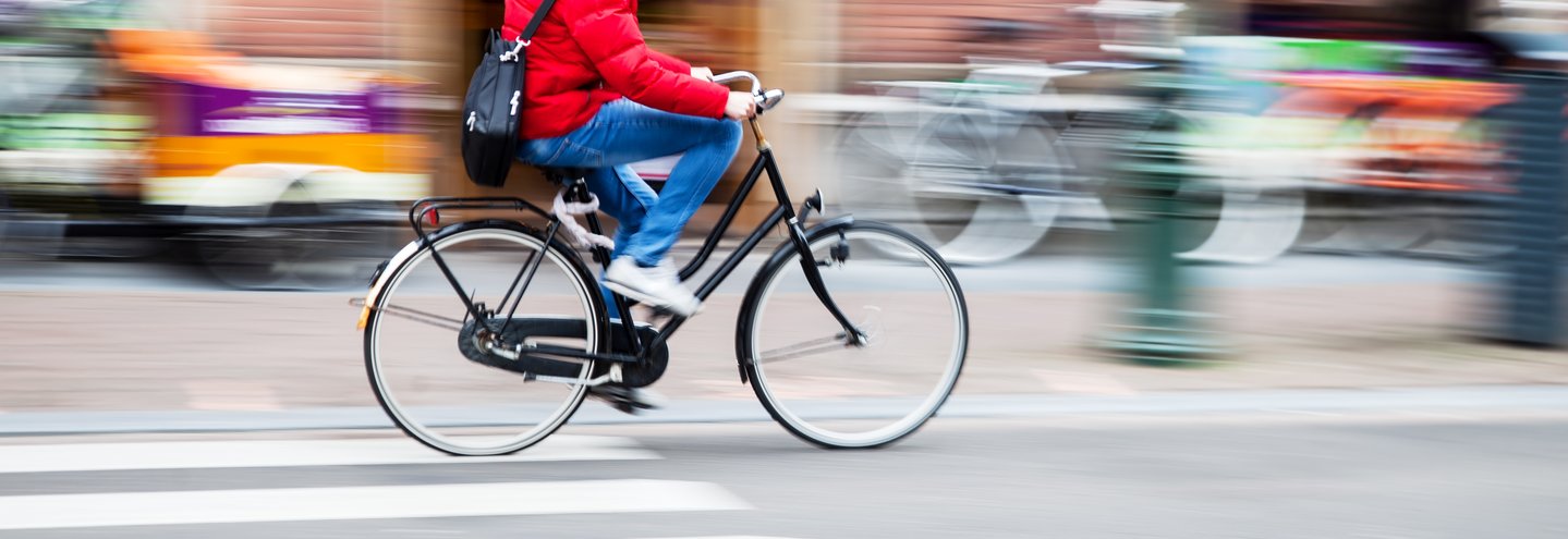 Das Foto zeigt einen Mann auf dem Rad in der Stadt fahrend.